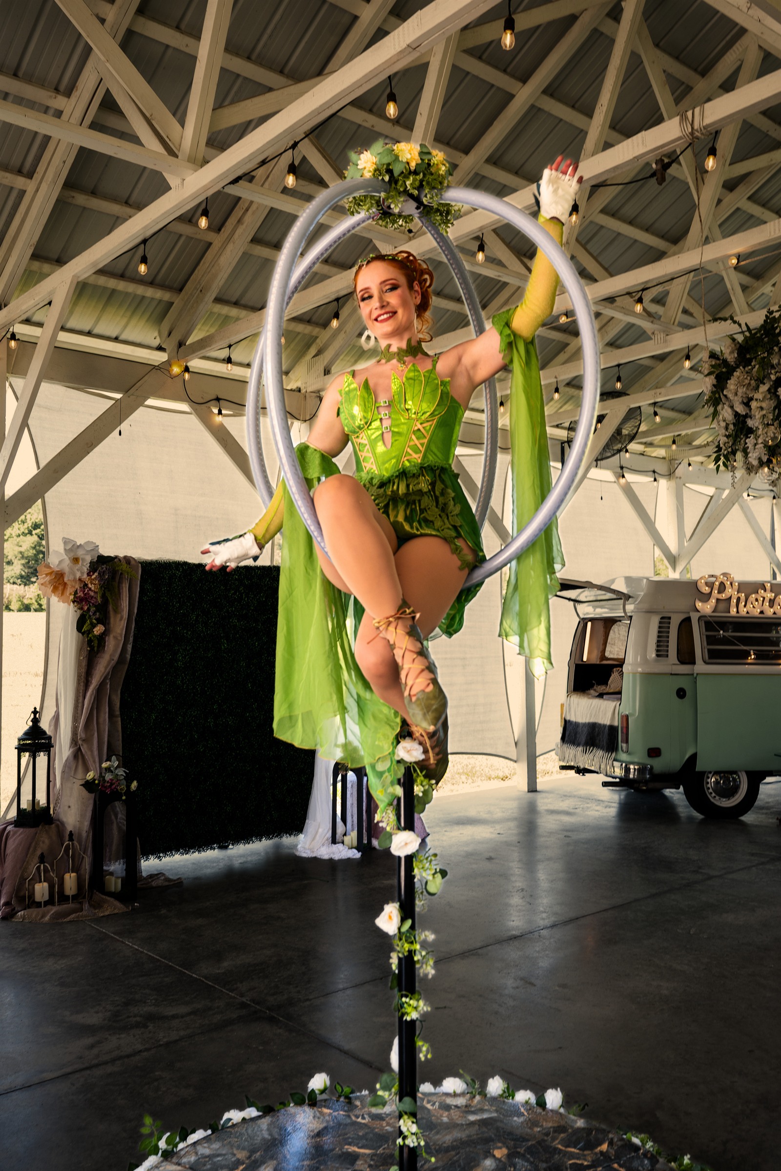 Aerial performer in a vivid green botanical costume posed within a suspended circular apparatus