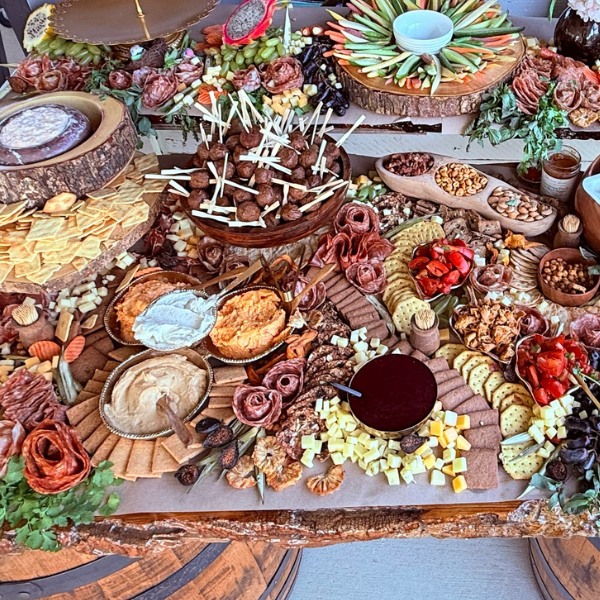 Grazing-table detail with sculpted charcuterie roses, cheeses, crackers and colorful accompaniments